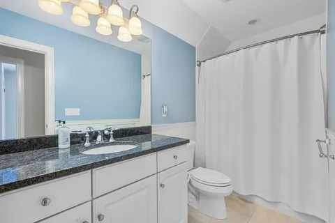a bathroom with a granite countertop sink vanity mirror and toilet