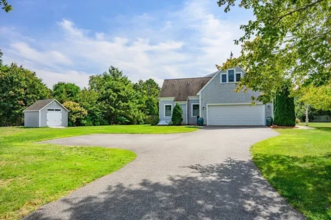 a front view of house with yard and trees in the background