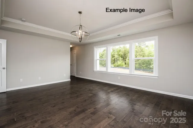 a view of an empty room with wooden floor closet and a window