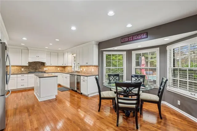 a kitchen with a table chairs wooden floors and a view of living room