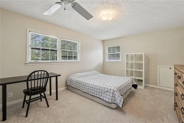 a bedroom with a bed chair and windows