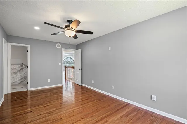 a view of empty room with wooden floor and ceiling fan