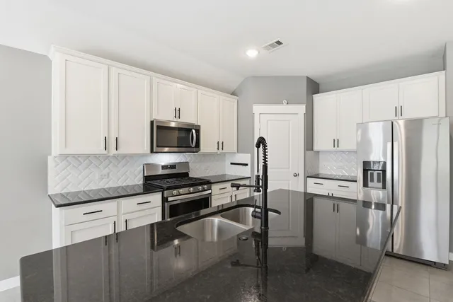 a kitchen with stainless steel appliances a refrigerator stove microwave and white cabinets