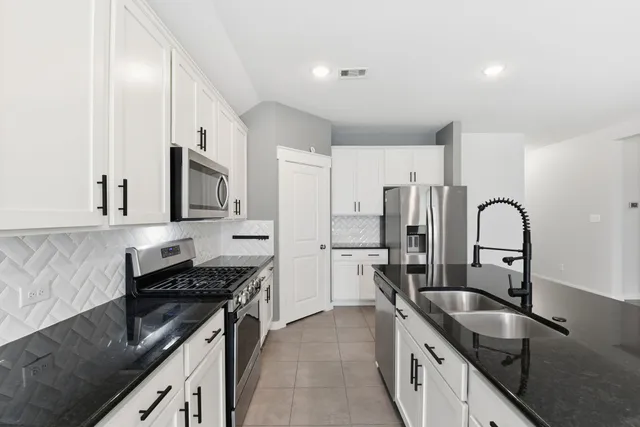 a kitchen with granite countertop a sink stainless steel appliances and cabinets