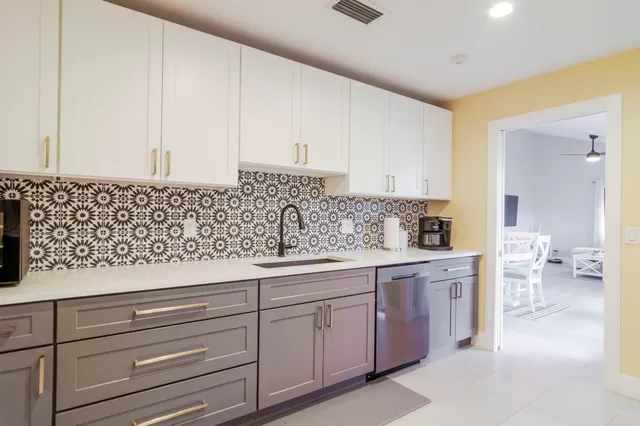a kitchen with white cabinets and sink