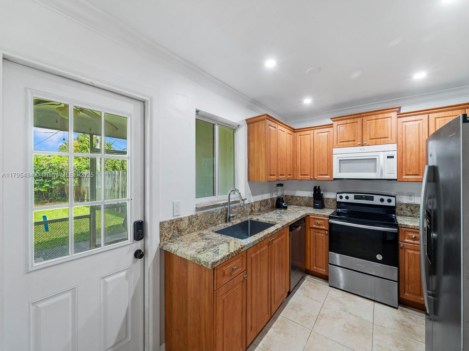 1761 Northeast 52nd Street, Unit 12 Fort Lauderdale, FL 33334 - Photo 16 of 19 a kitchen with stainless steel appliances granite countertop a stove a sink and a refrigerator