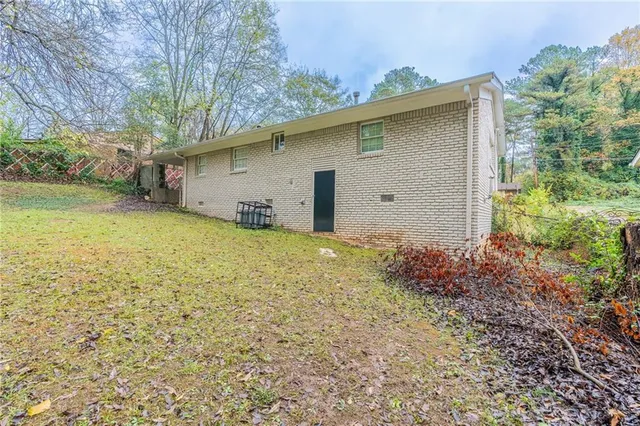 a backyard of a house with plants and large tree
