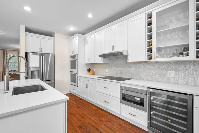 a kitchen with stainless steel appliances granite countertop a stove and a refrigerator with white cabinets