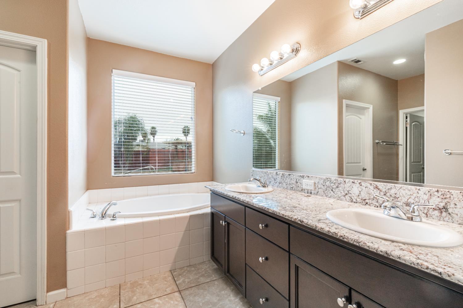 863 Legacy Drive Lemoore, CA 93245 - Photo 25 of 33 a bathroom with a granite countertop tub sink and mirror