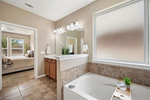 a bathroom with a tub a sink and a mirror