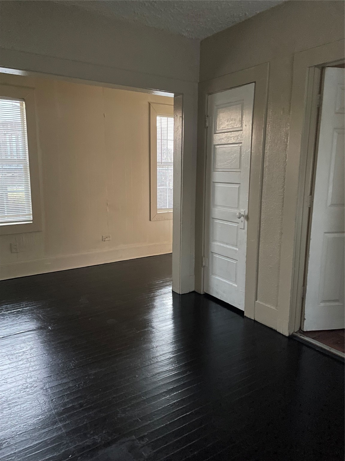 3310 Campbell Street Houston, TX 77026 - Photo 8 of 9 an empty room with wooden floor and windows with curtains