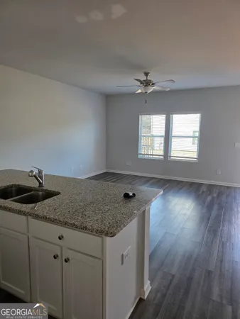a kitchen with granite countertop a sink cabinets and wooden floor