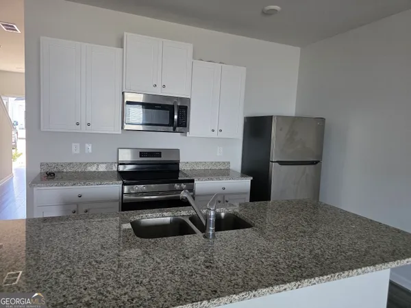 a kitchen with a refrigerator sink and cabinets
