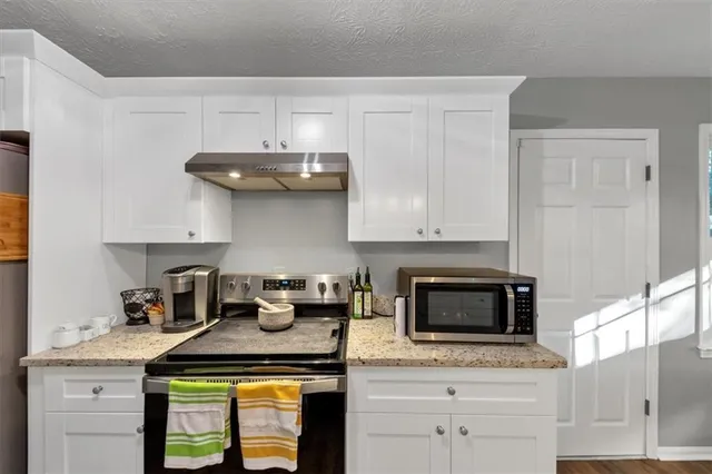 a kitchen with granite countertop stainless steel appliances a stove and cabinets