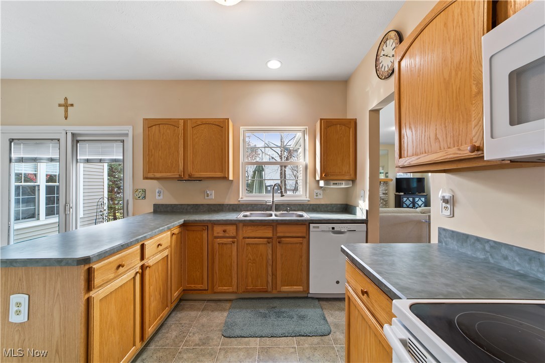 4461 Sexton Road Cleveland, OH 44105 - Photo 8 of 47 Kitchen with white appliances, dark countertops, a peninsula, brown cabinets, and recessed lighting