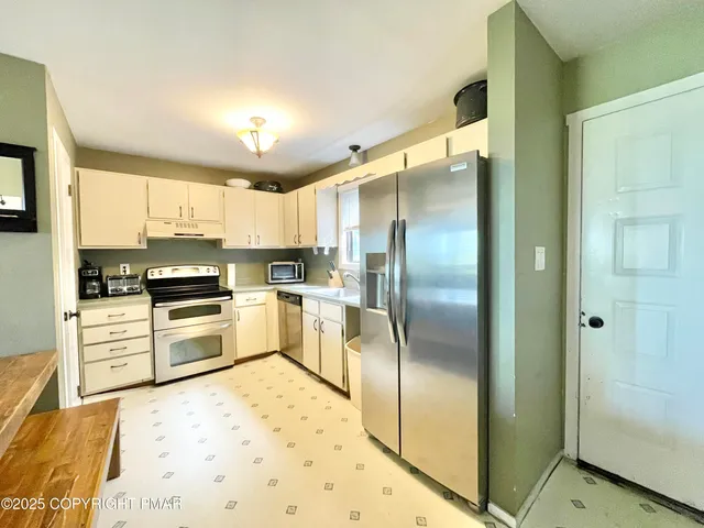 a kitchen with granite countertop a refrigerator and white cabinets