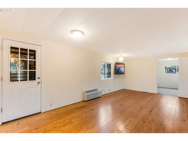 a view of an empty room with window and wooden floor