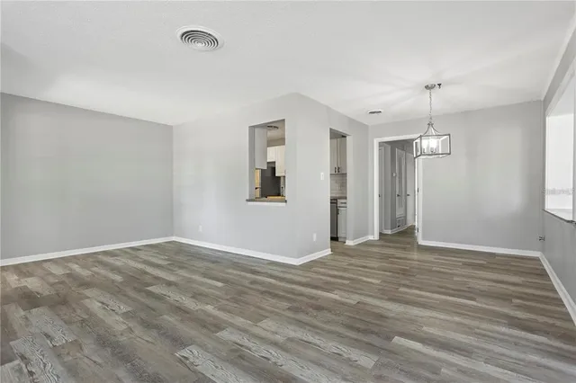 a view of an empty room with window and wooden floor