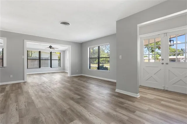 a view of an empty room with wooden floor and a window