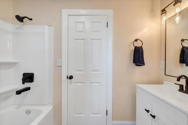 a bathroom with a tub sink and mirror