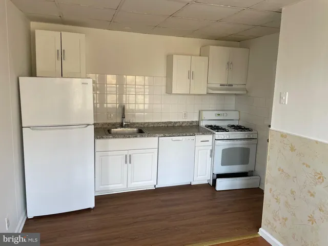 a kitchen with granite countertop white cabinets and white appliances