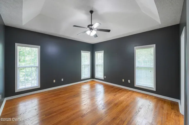 a view of an empty room with window and wooden floor