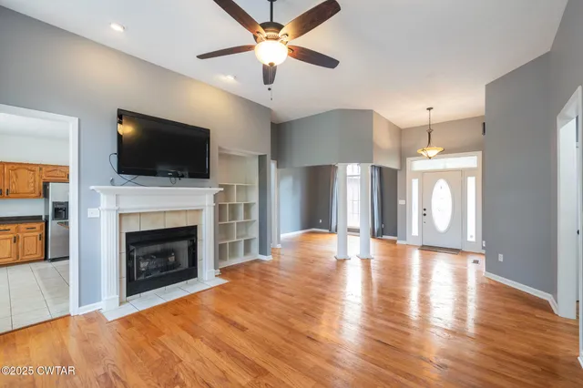 a view of a livingroom with a fireplace a ceiling fan and fire place