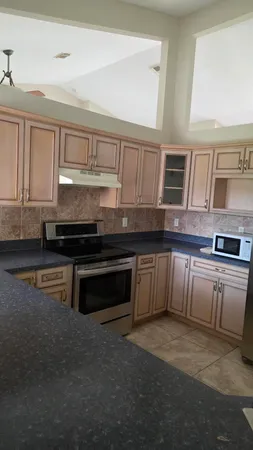 a kitchen with stainless steel appliances granite countertop a stove a sink and a microwave