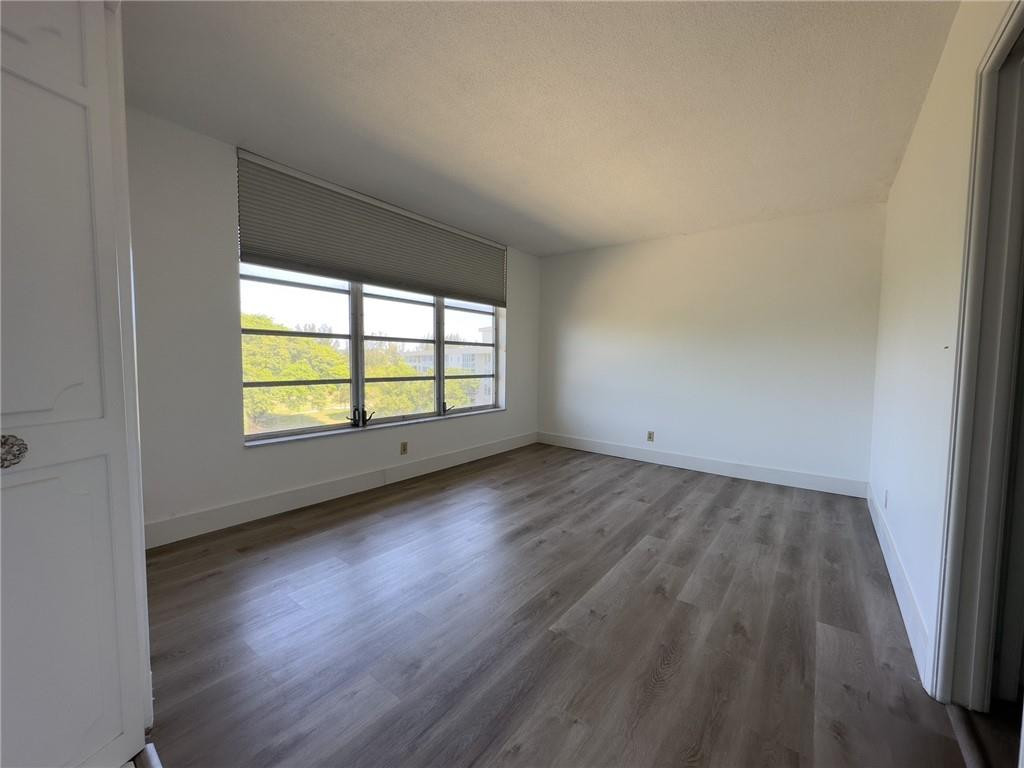 2650 South Course Drive, Unit 603 Pompano Beach, FL 33069 - Photo 8 of 25 an empty room with wooden floor and windows