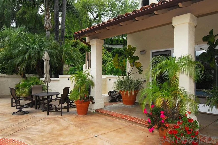 6515 Poco Lago Rancho Santa Fe, CA 92091 - Photo 14 of 25 a view of a patio with table and chairs potted plants and palm tree