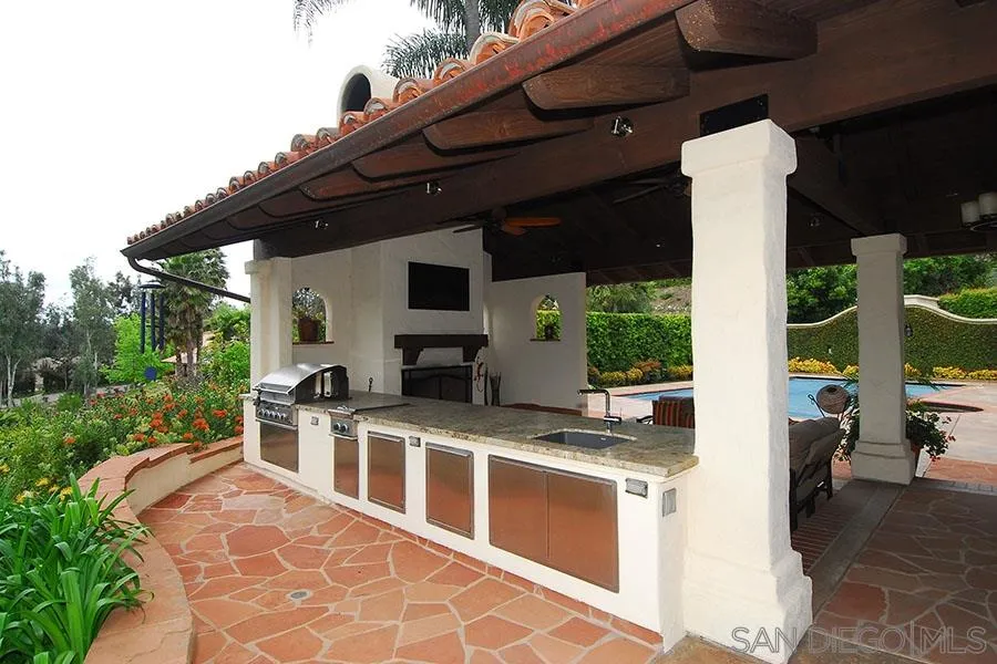6515 Poco Lago Rancho Santa Fe, CA 92091 - Photo 16 of 25 a view of a patio with table and chairs potted plants with palm trees