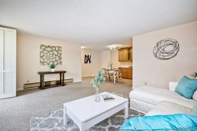 a living room with furniture and a kitchen appliance view