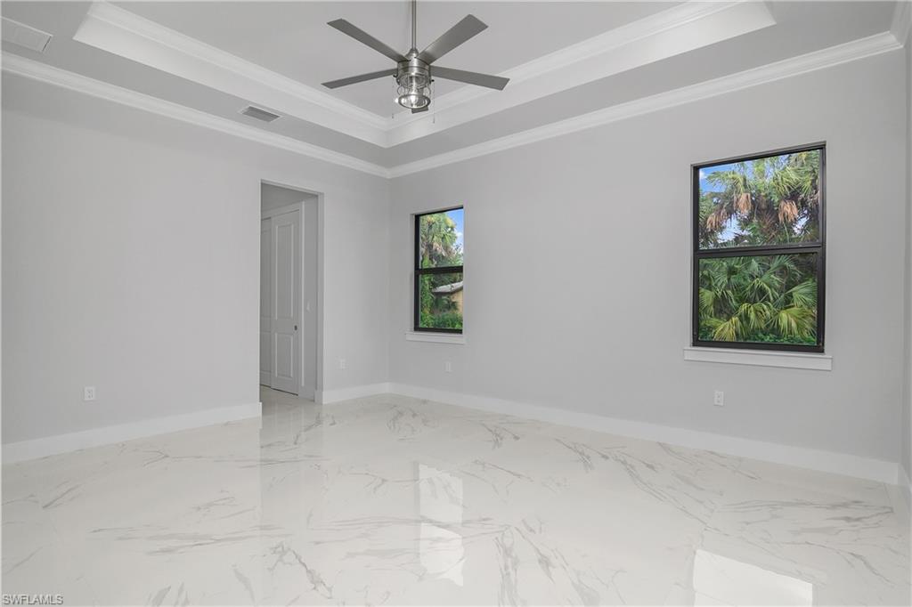 791 14th Street Northeast Naples, FL 34120 - Photo 16 of 46 Empty room with ornamental molding, a ceiling fan, light marble finish flooring, and a tray ceiling