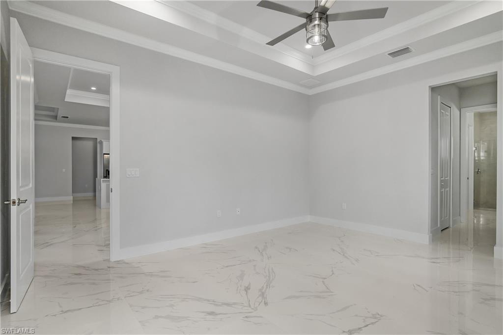 791 14th Street Northeast Naples, FL 34120 - Photo 17 of 46 Spare room featuring crown molding, a tray ceiling, light marble finish floors, recessed lighting, and ceiling fan