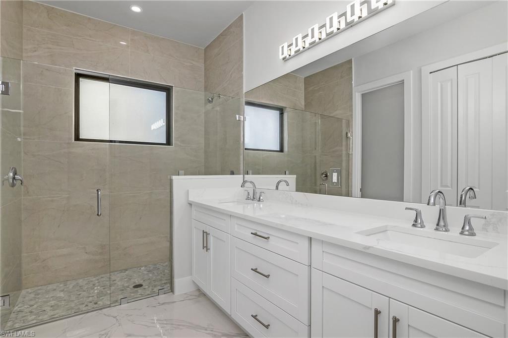 791 14th Street Northeast Naples, FL 34120 - Photo 18 of 46 Full bath with a shower stall, double vanity, light marble finish floors, and a closet
