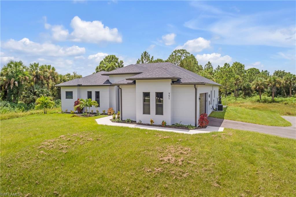791 14th Street Northeast Naples, FL 34120 - Photo 2 of 46 View of front of home with a front yard, driveway, roof with shingles, a garage, and stucco siding