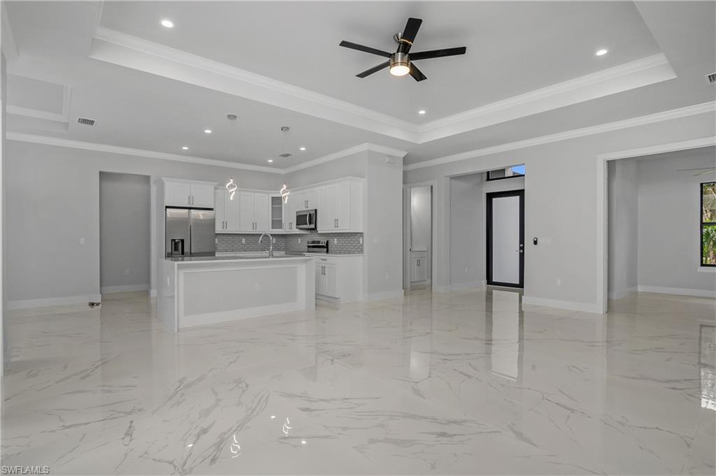 791 14th Street Northeast Naples, FL 34120 - Photo 7 of 46 Unfurnished living room with a ceiling fan, ornamental molding, recessed lighting, and a tray ceiling
