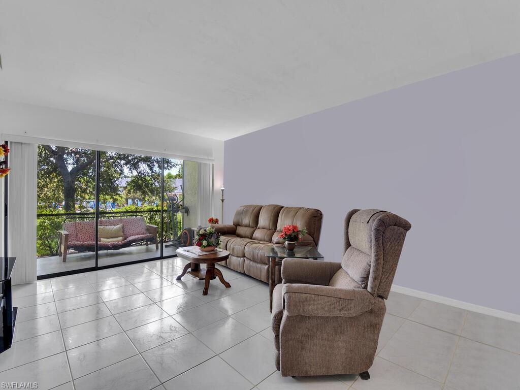 1208 Commonwealth Circle, Unit J102 Naples, FL 34116 - Photo 8 of 21 a living room with furniture and large windows