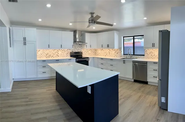 a kitchen with kitchen island a sink dishwasher stove and refrigerator with wooden floor