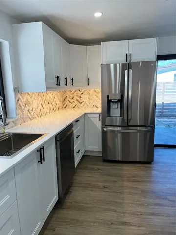 a kitchen with kitchen island granite countertop a sink and refrigerator