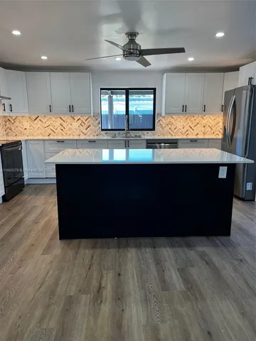 a room with kitchen island granite countertop wooden floors and a large window