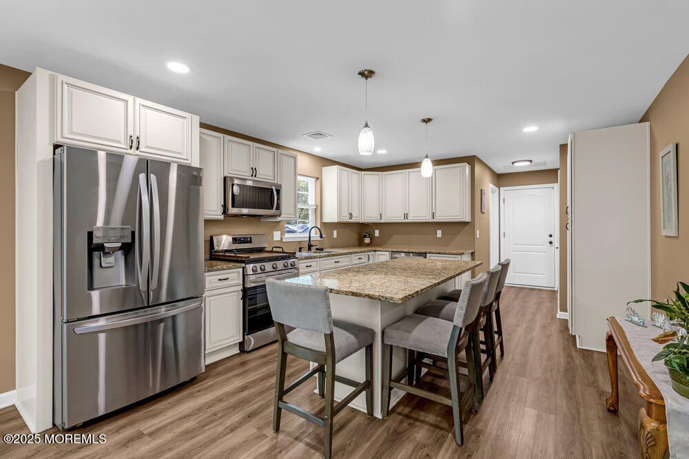 119 Darien Road Howell, NJ 07731 - Photo 15 of 47 a kitchen with stainless steel appliances a refrigerator a stove a sink a dining table and chairs with wooden floor