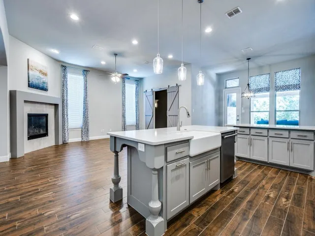 a large kitchen with kitchen island a sink dishwasher a stove and a wooden floors