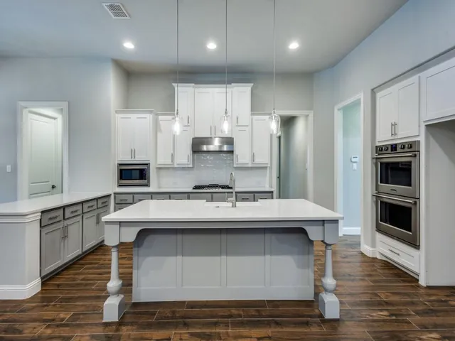 a kitchen with kitchen island stainless steel appliances a sink stove and oven