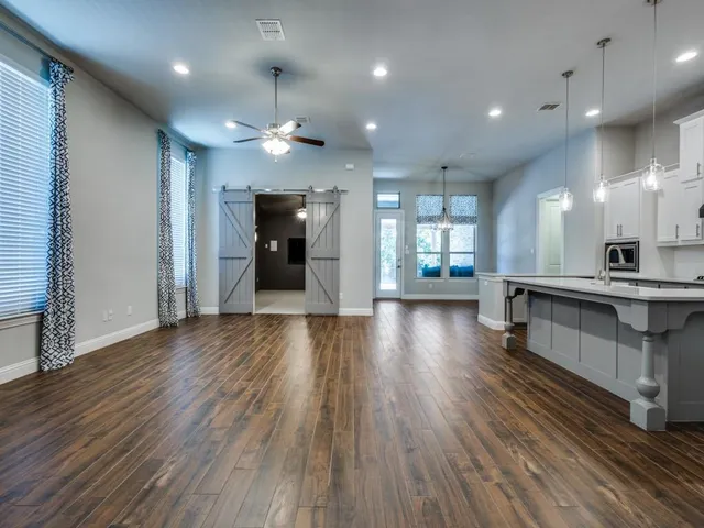 an open kitchen with white cabinets stainless steel appliances and wooden floor