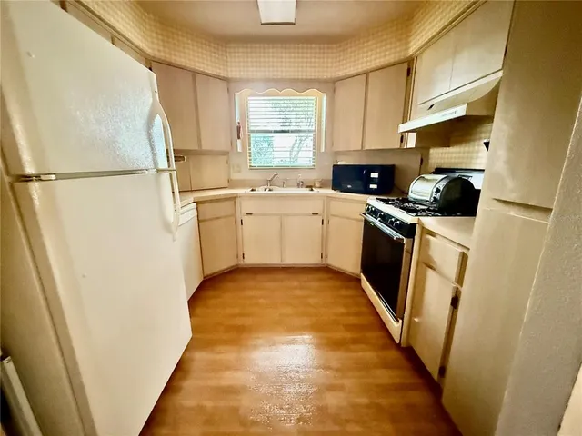 a kitchen with a sink a refrigerator a stove top oven and cabinets