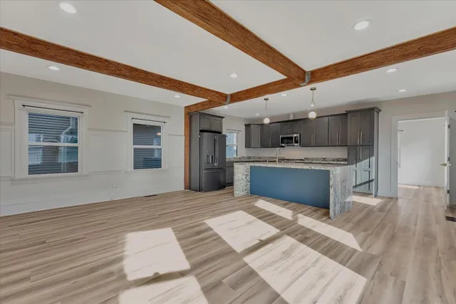 a large white kitchen with stainless steel appliances kitchen island a stove a refrigerator a oven and a sink with granite countertops