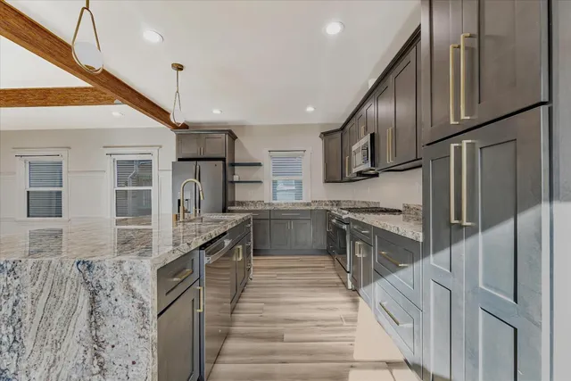 a kitchen with stainless steel appliances granite countertop a refrigerator a stove and a sink