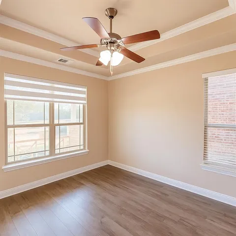an empty room with wooden floor fan and windows