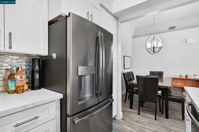 a kitchen with stainless steel appliances granite countertop a dining table chairs and a refrigerator